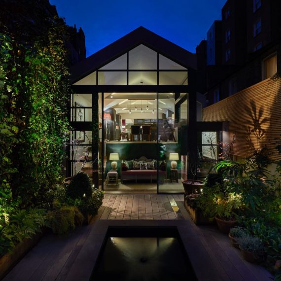 Garden of modern London house with pond and wooden slatted wallsdesigned by Tania Compton and lit by John Cullen