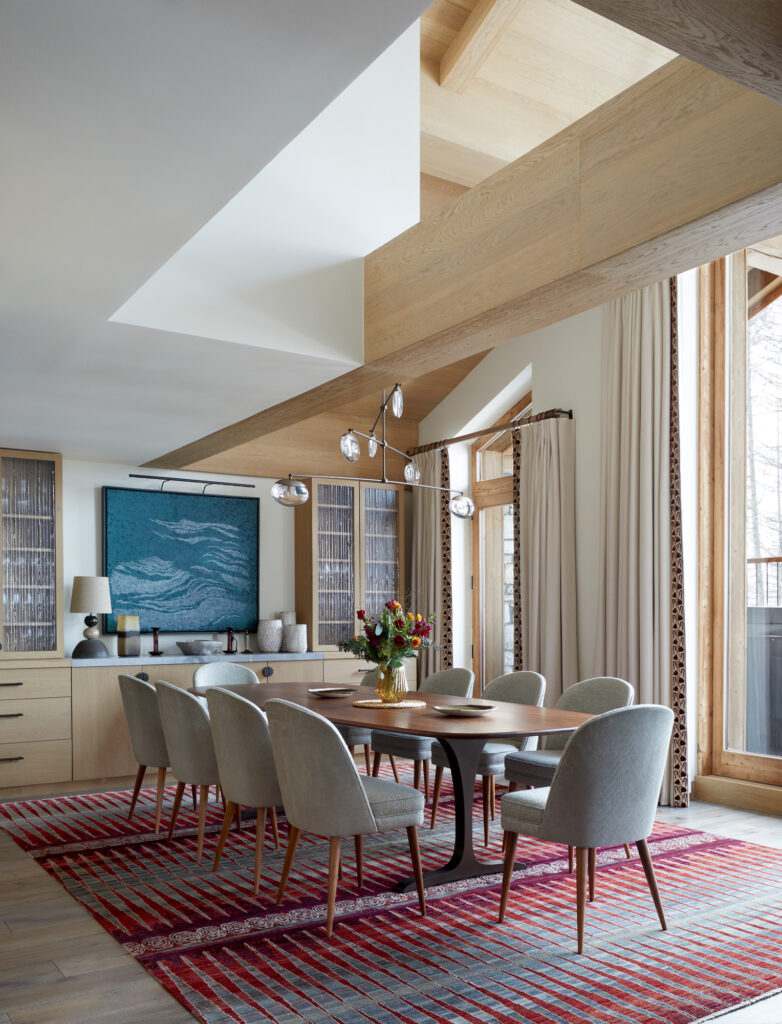 Luxury family ski chalet dining room with Luke Irwin rug and Tom Faulkner dining table, Ochre pendant light and double height ceilings