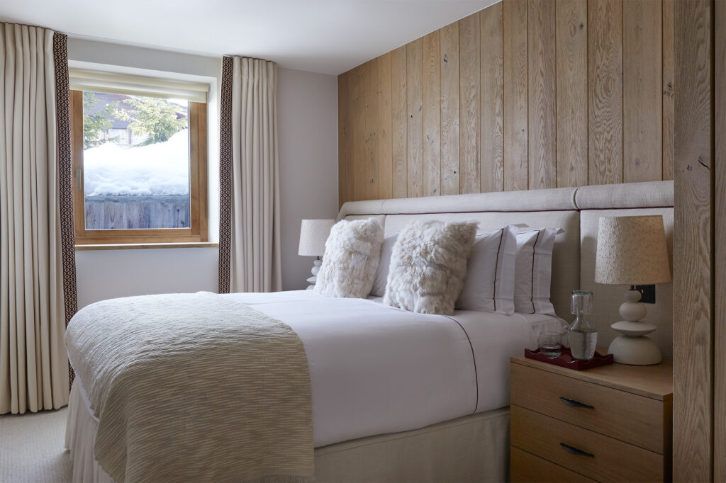 Luxury chalet bedroom with oak clad walls and full width headboard matching headboard and valance