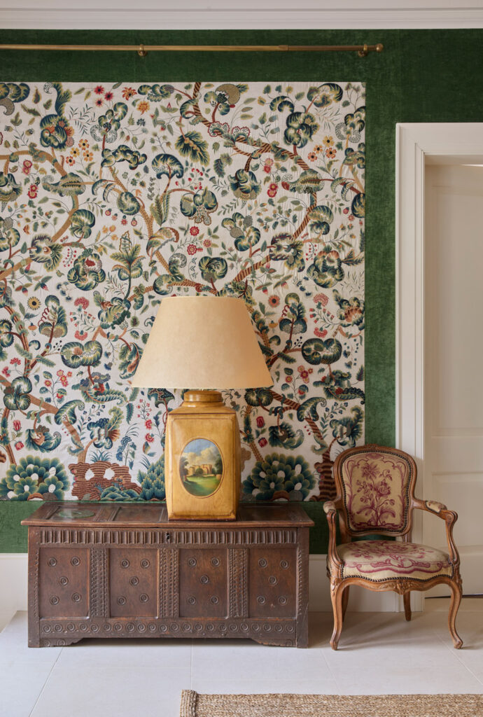 Restored 18th century crewelwork panels in country house entrance hall with yellow velum antique lamp